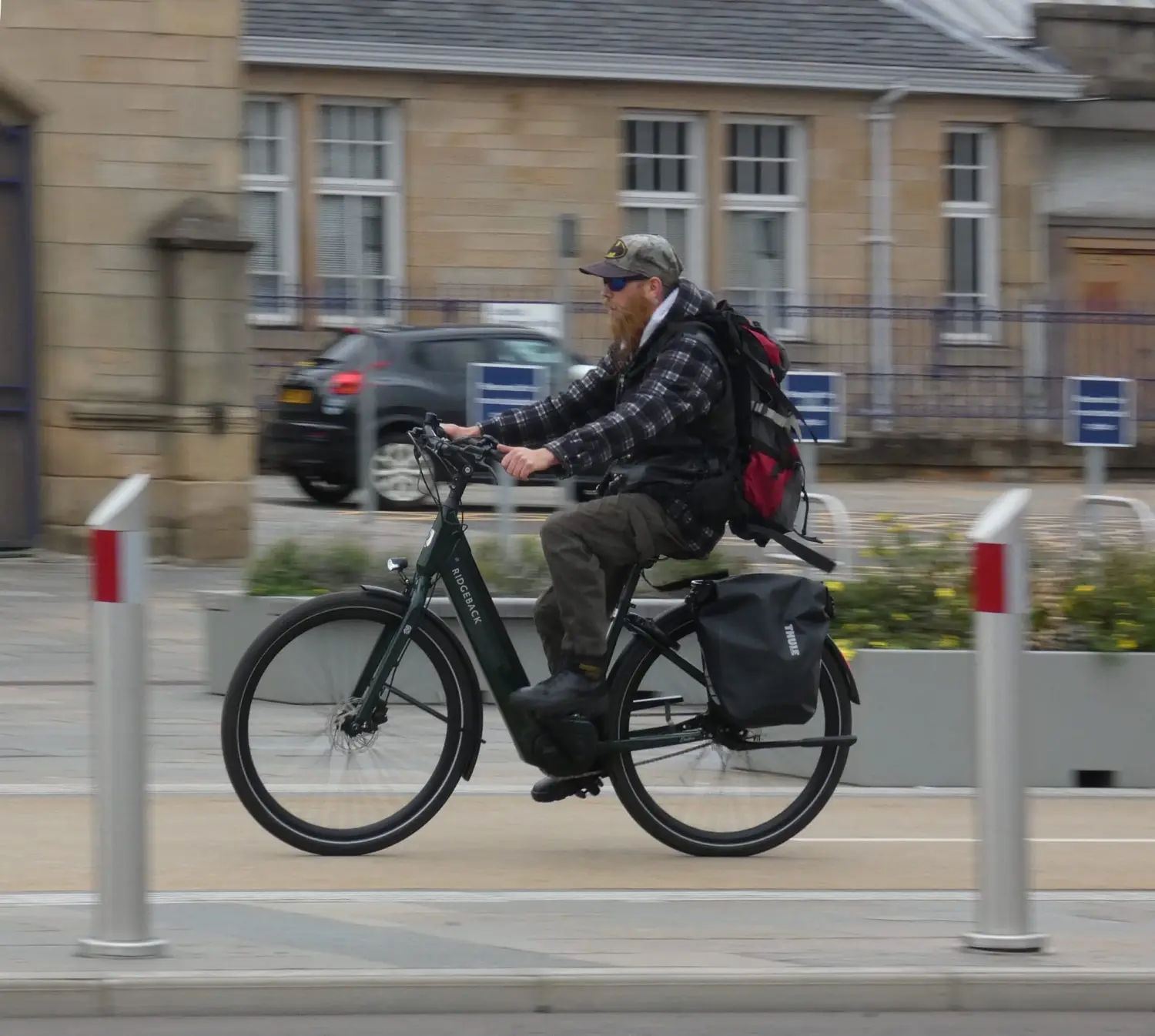 A photo of a cyclist enjoying high quality cycle paths in an urban environment, passing by a railway station.
