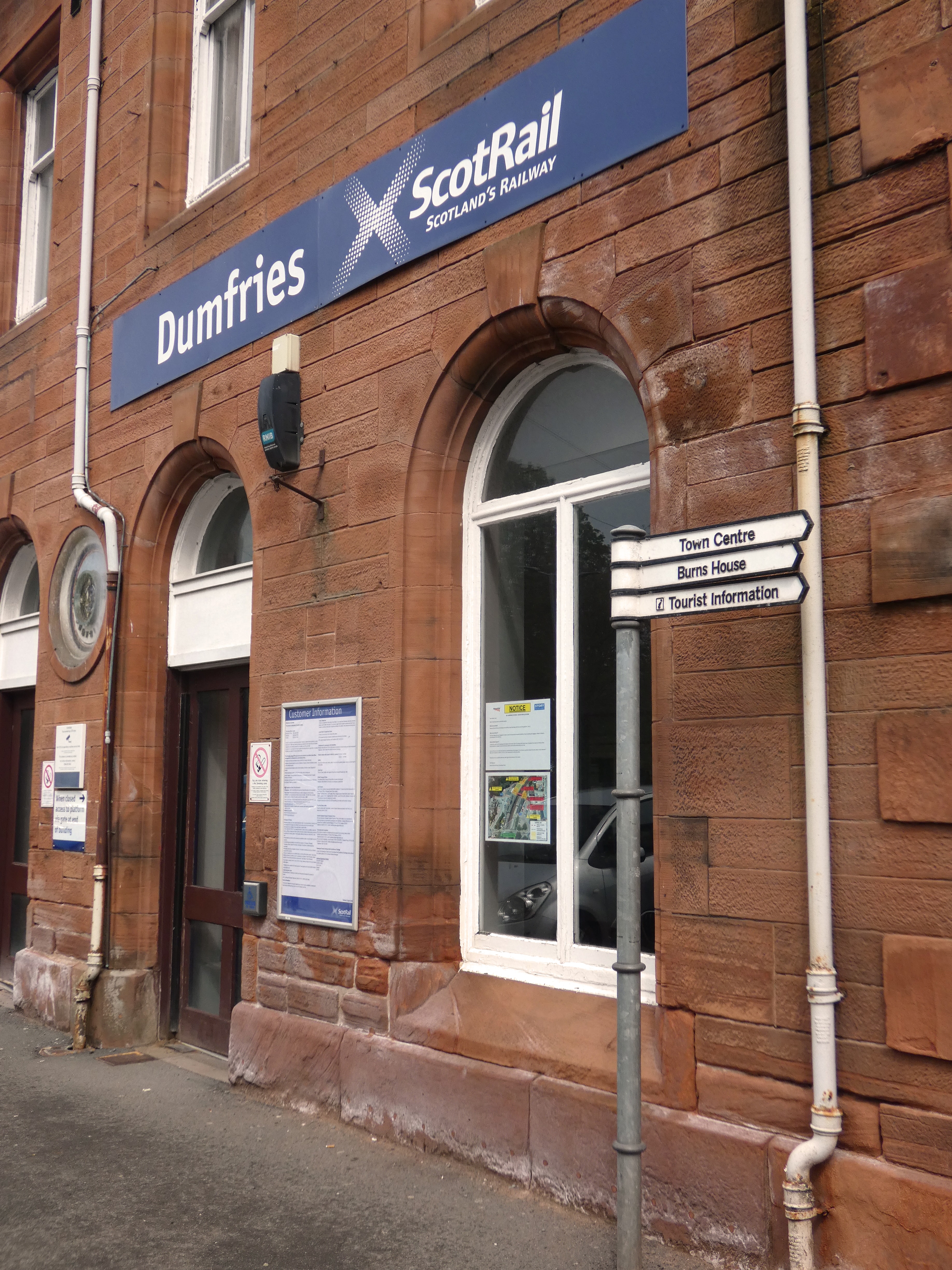 Finger post sign outside the station with signs to Town Centre, Burns House and Tourist Information all pointing the same way