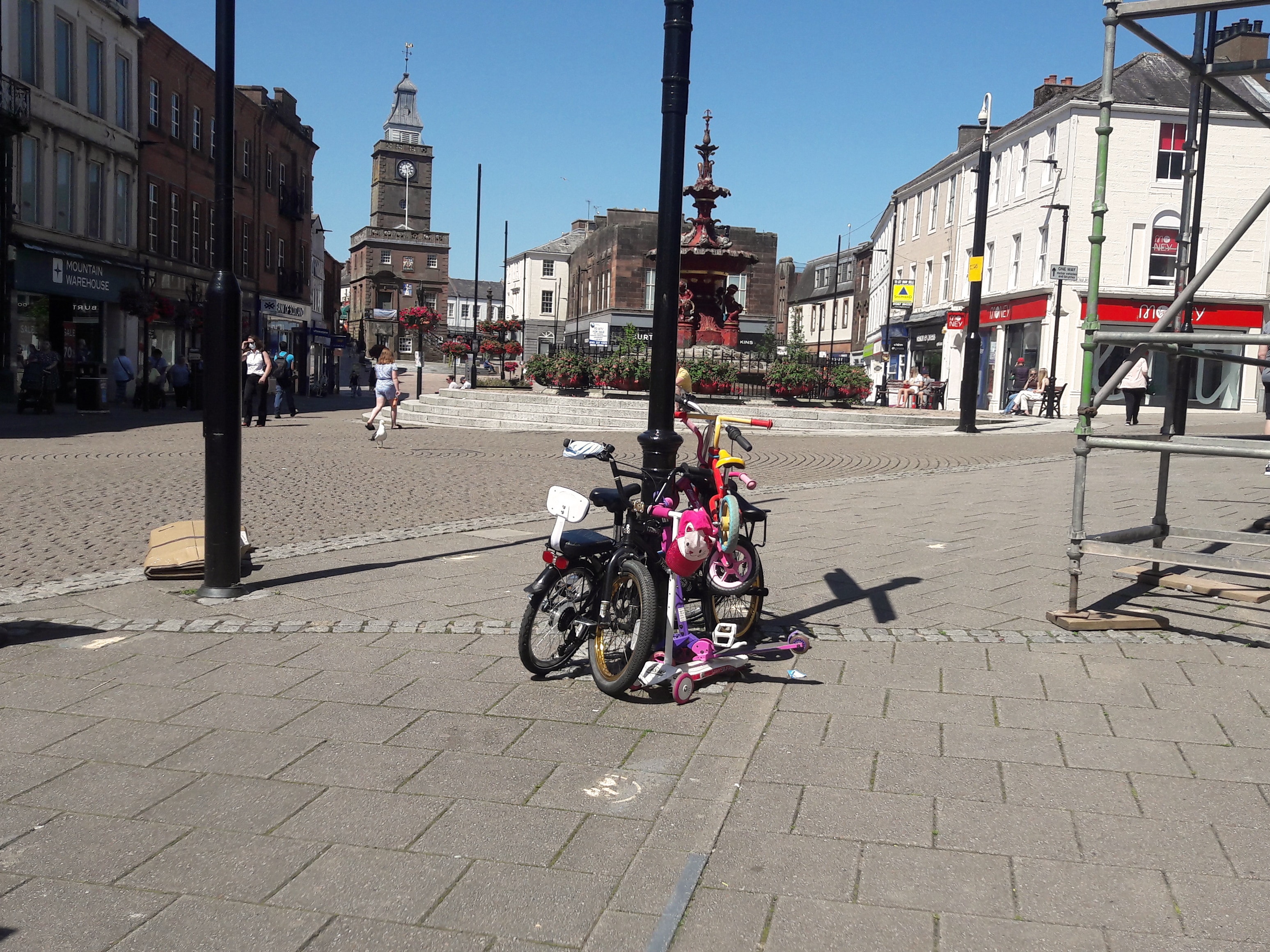 Adults and childrens bikes plus a scooter locked to a lamppost on the high street